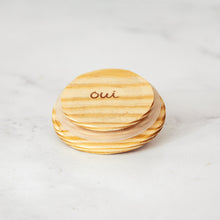 A wooden lid that fits a Oui by Yoplait glass yogurt jar.
