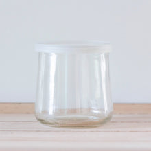 A clear, empty, unlabeled Oui by Yoplait yogurt jar with a clear lid.
